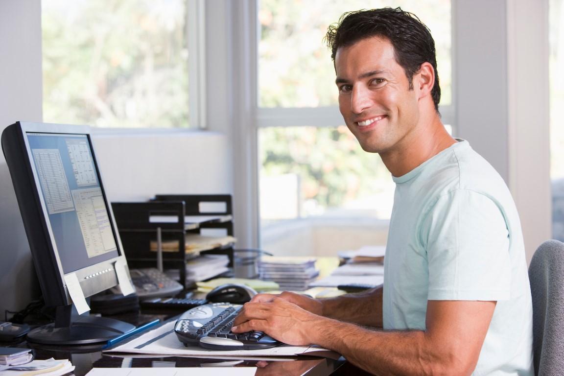 Man in home office using computer and smiling Bookkeeping principles